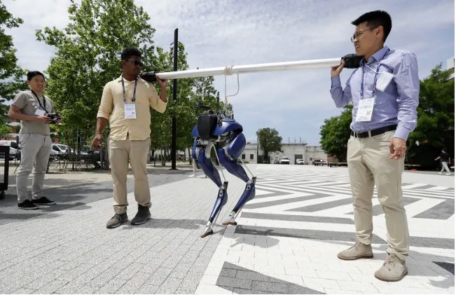 Two engineering students carrying a bi-ped robot outside of the Pennovation Center